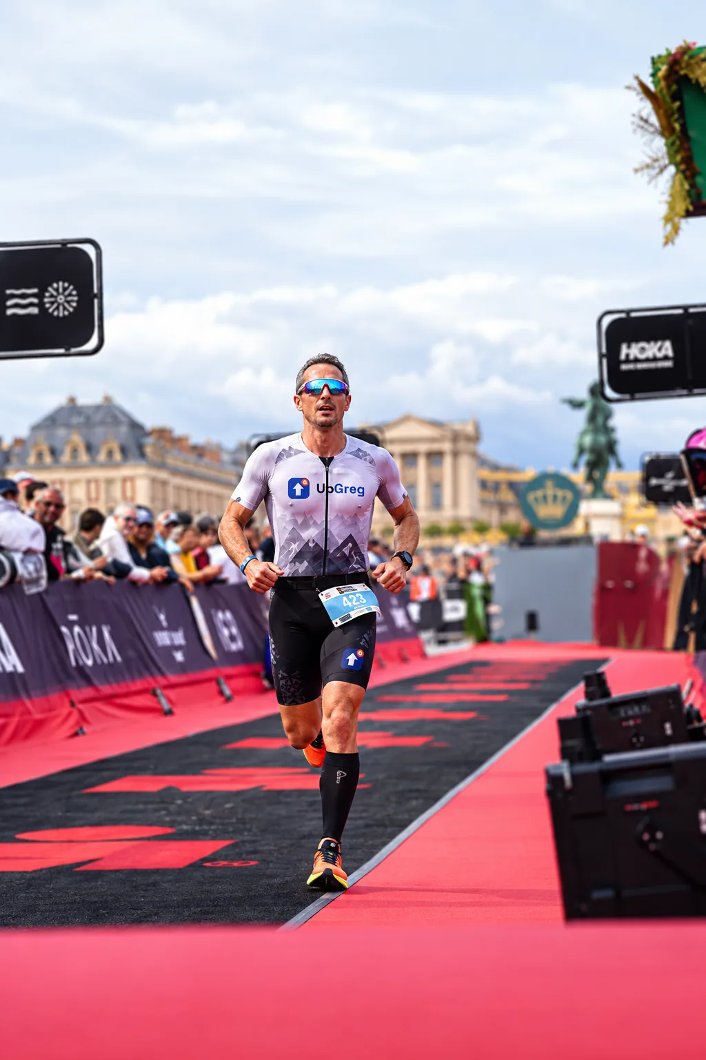 Finish of the Versailles 70.3 on 11 October 2026, bib 423 in an UpGreg trisuit on the red carpet, the Château de Versailles behind